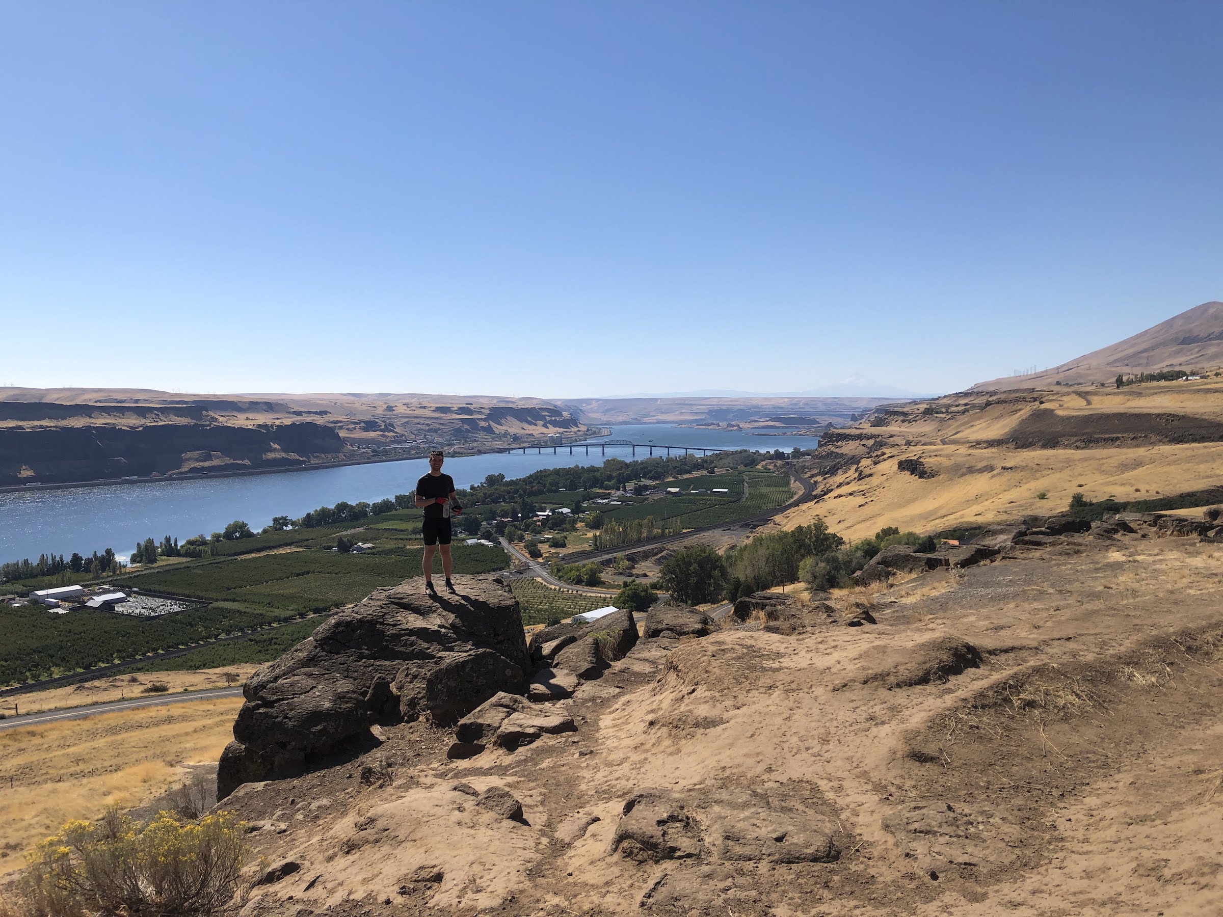 a man stands on a rock at the top of a cliff overlooking the Columbia river