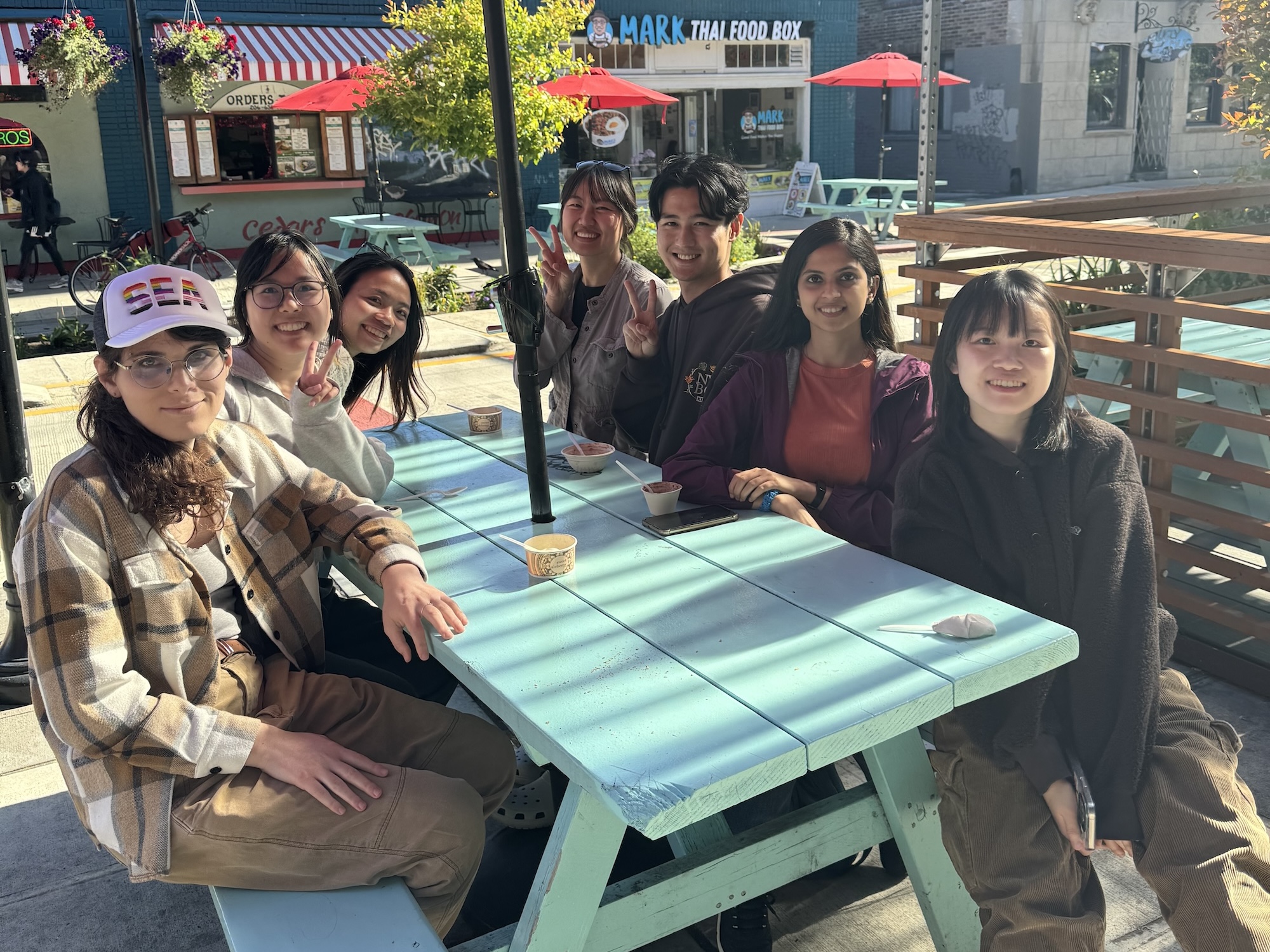 photo of lab members sitting around a picnic table in the university district of seattle