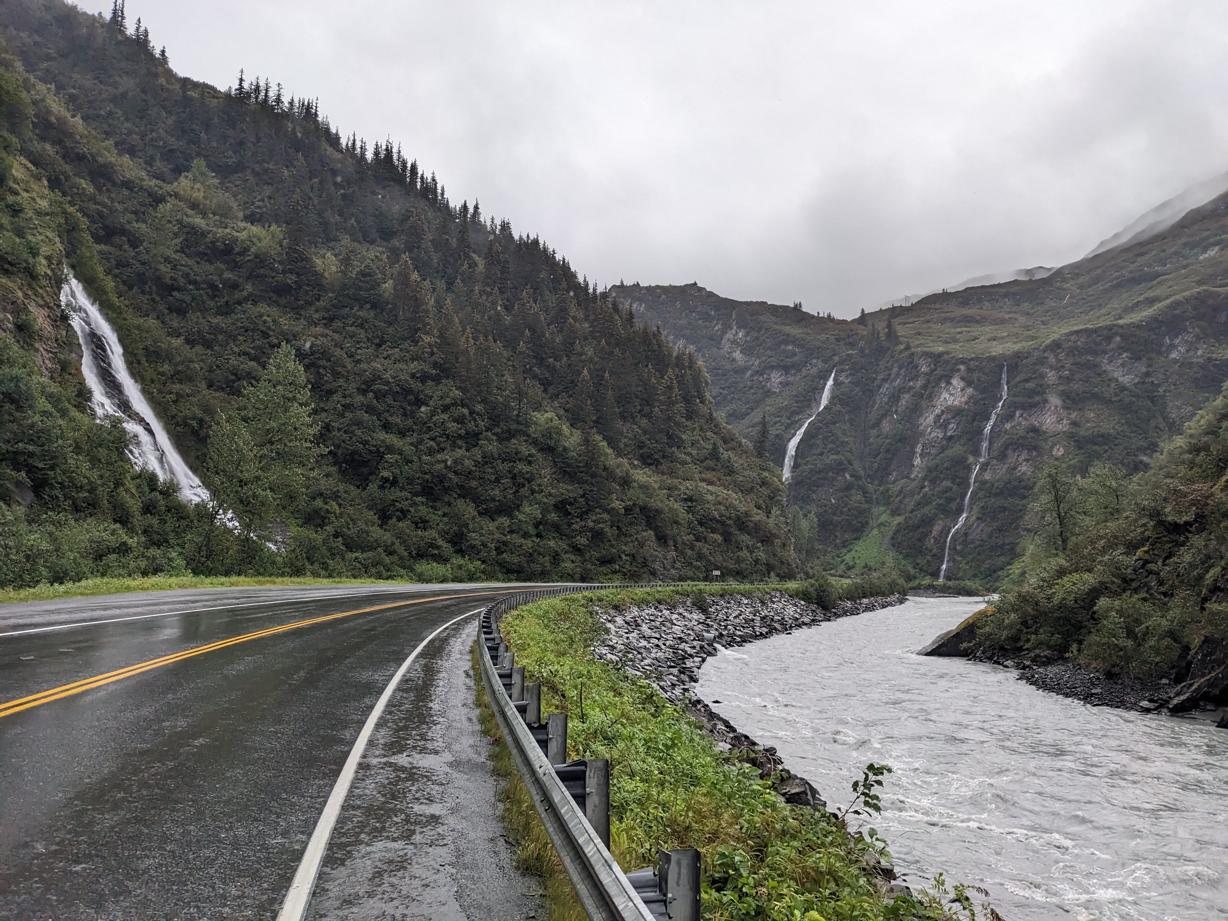 a road by a river with waterfalls on both sides