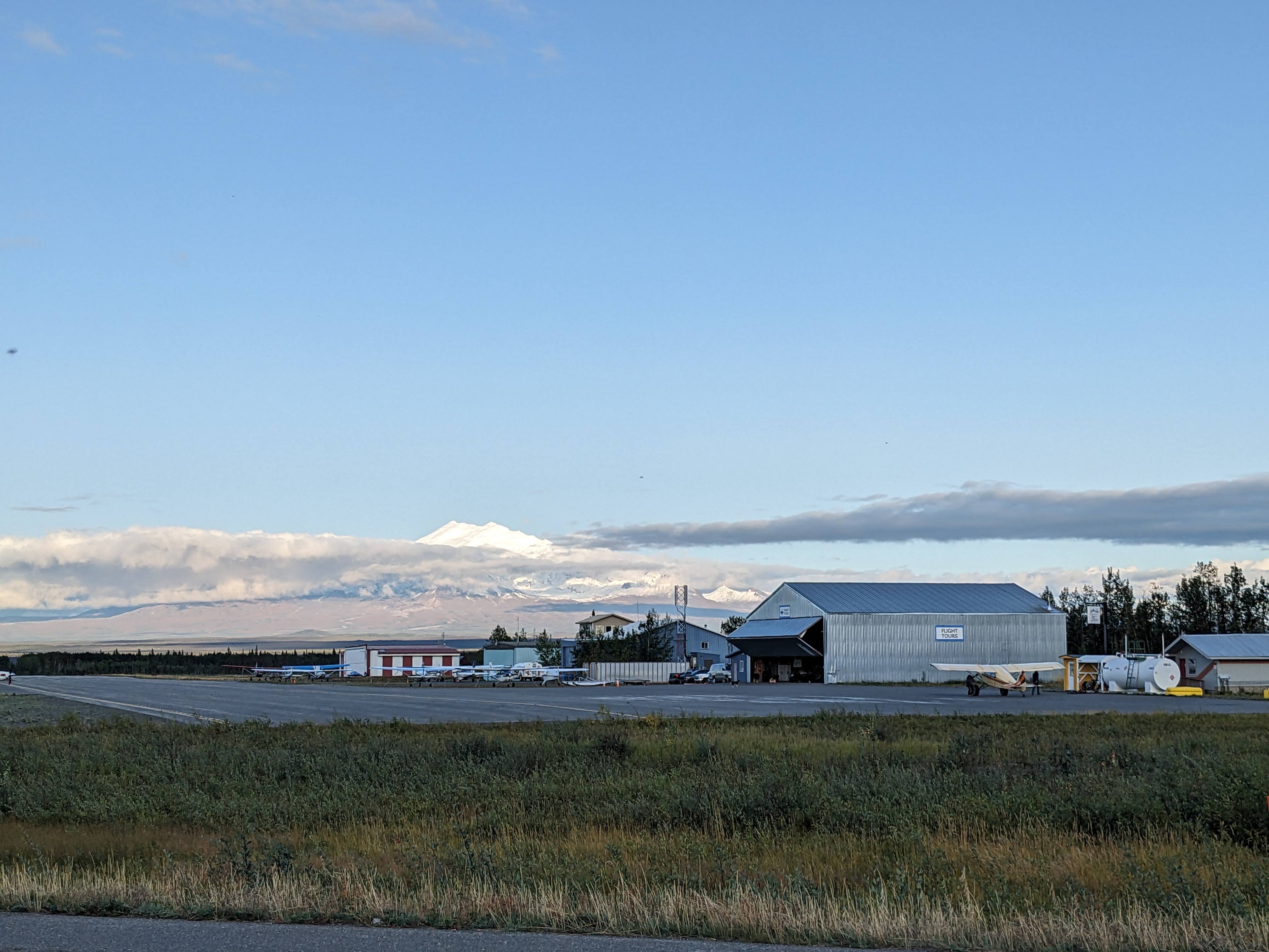 Wrangell St Elias rising above the clouds behind a small airport