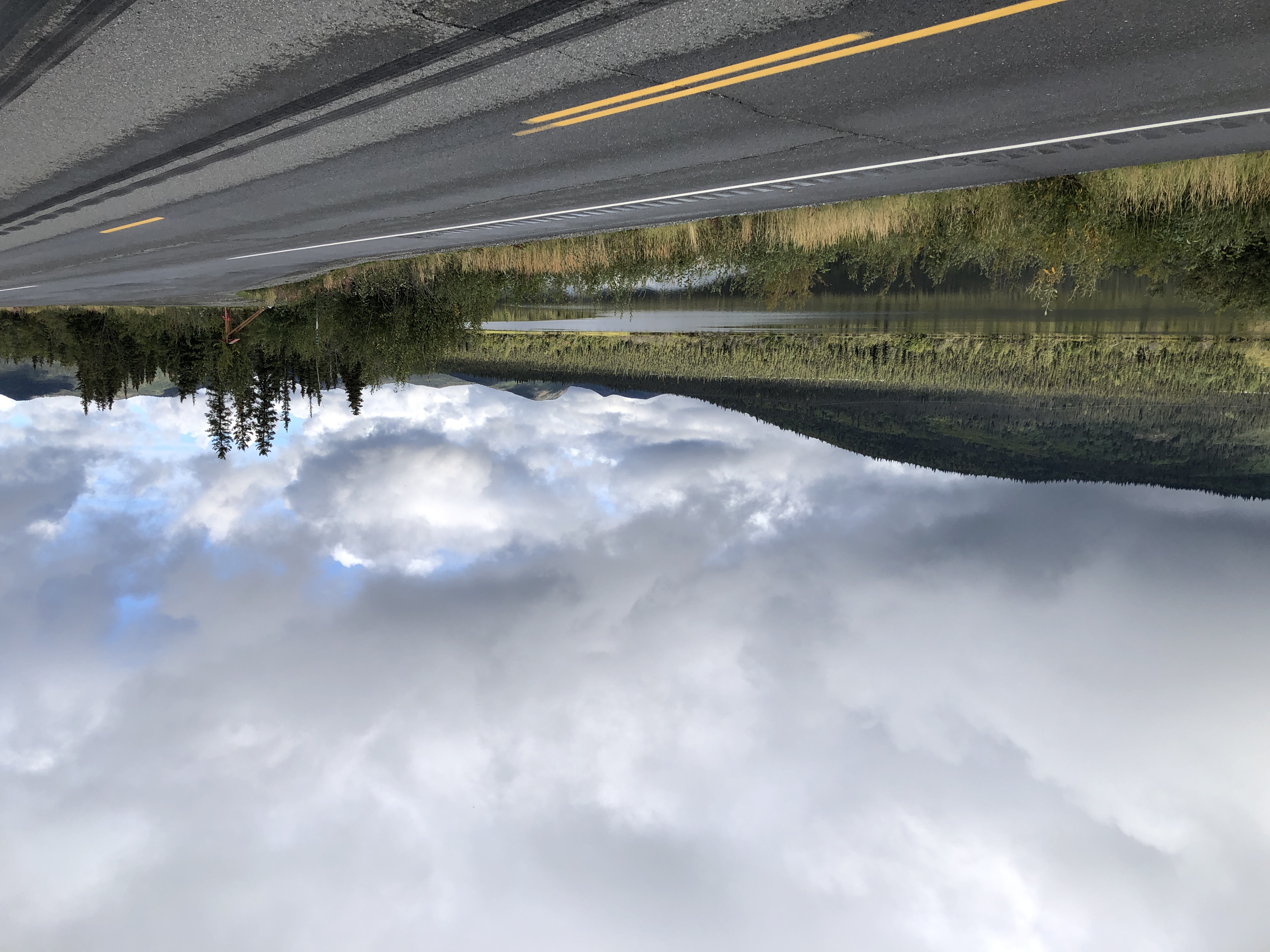 a road with river, hills, and clouds in the background