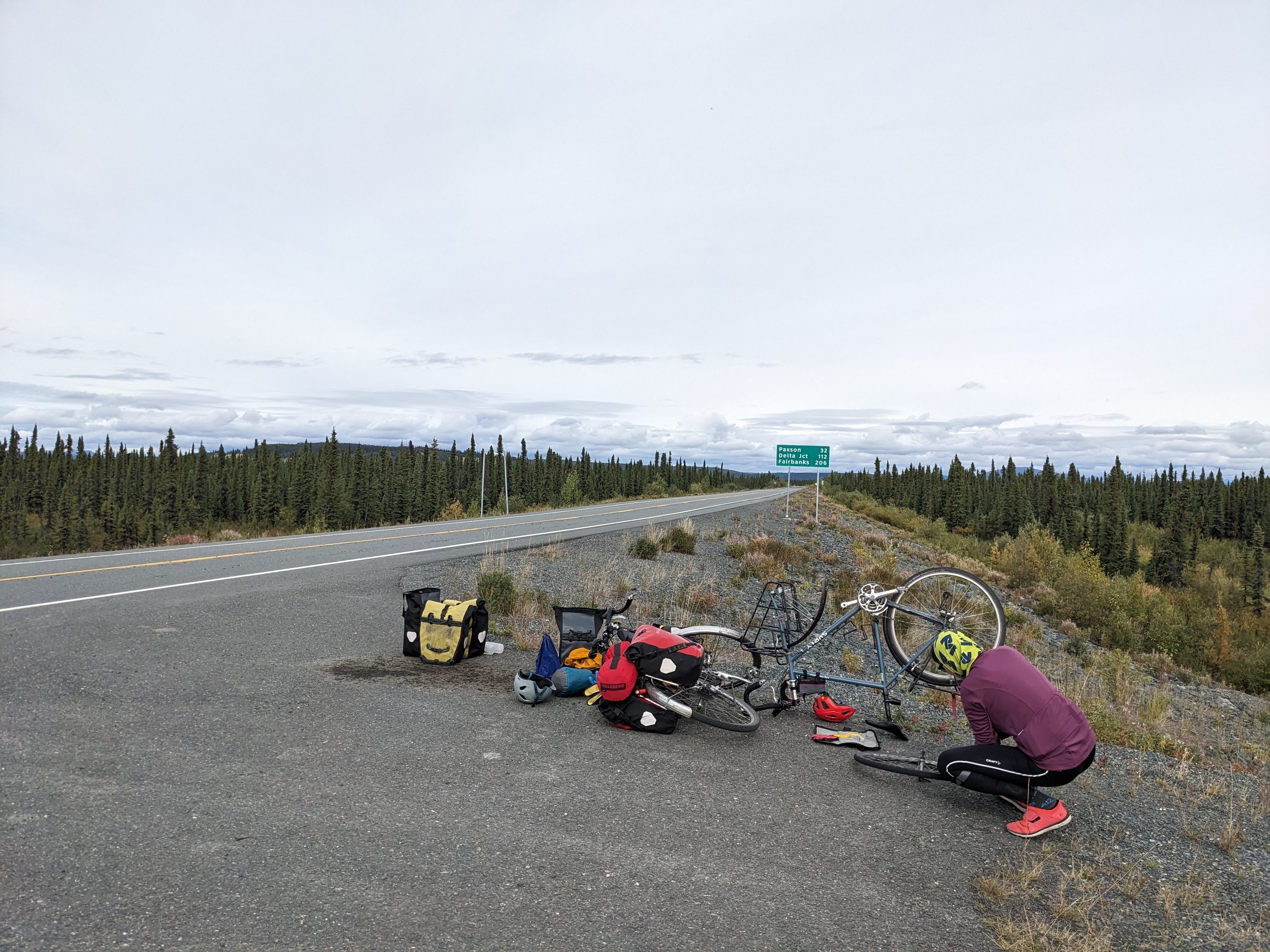 woman fixing a flat in a bicycle on the side of the road