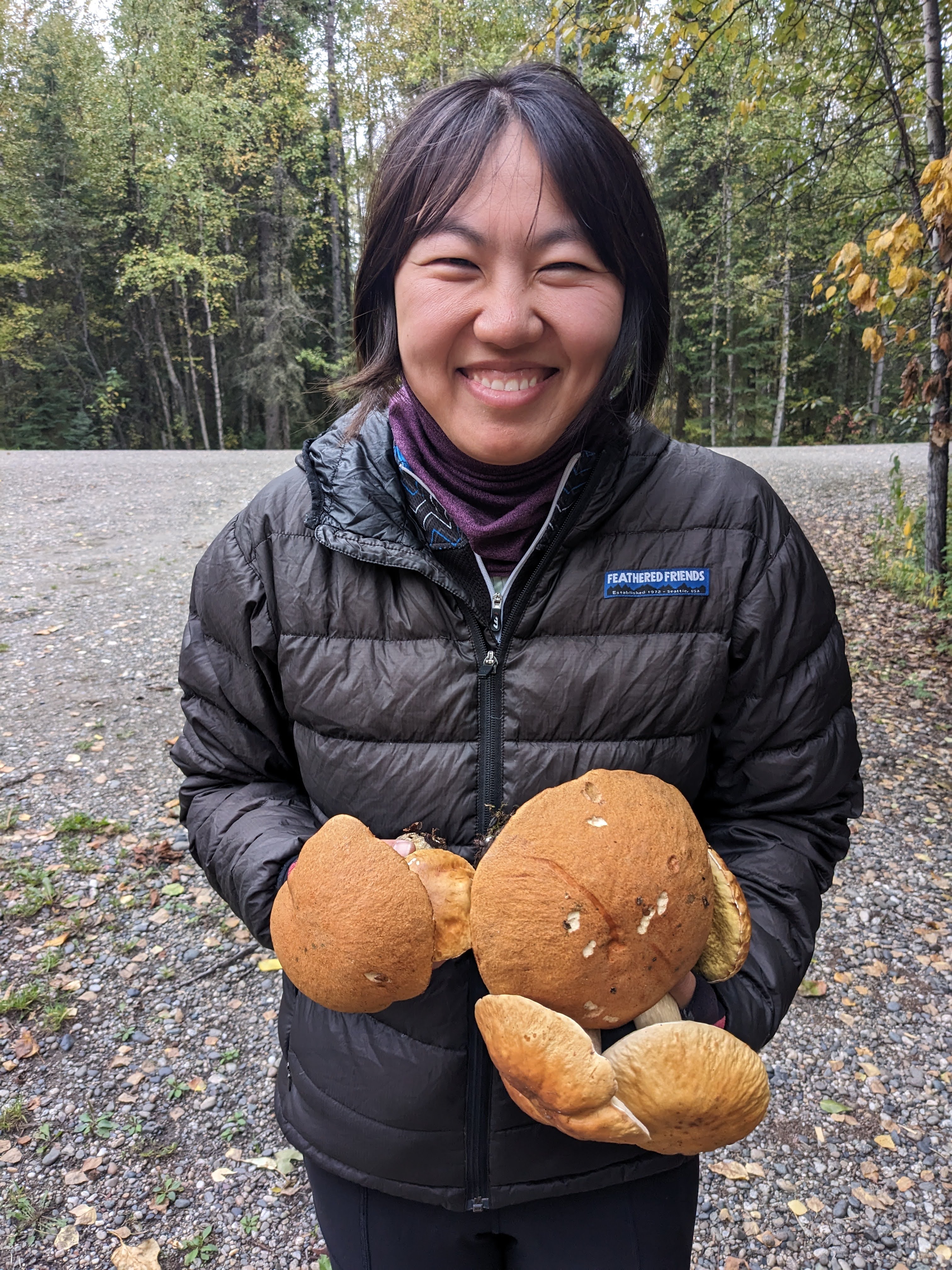 a woman happily holding many porcini mushrooms