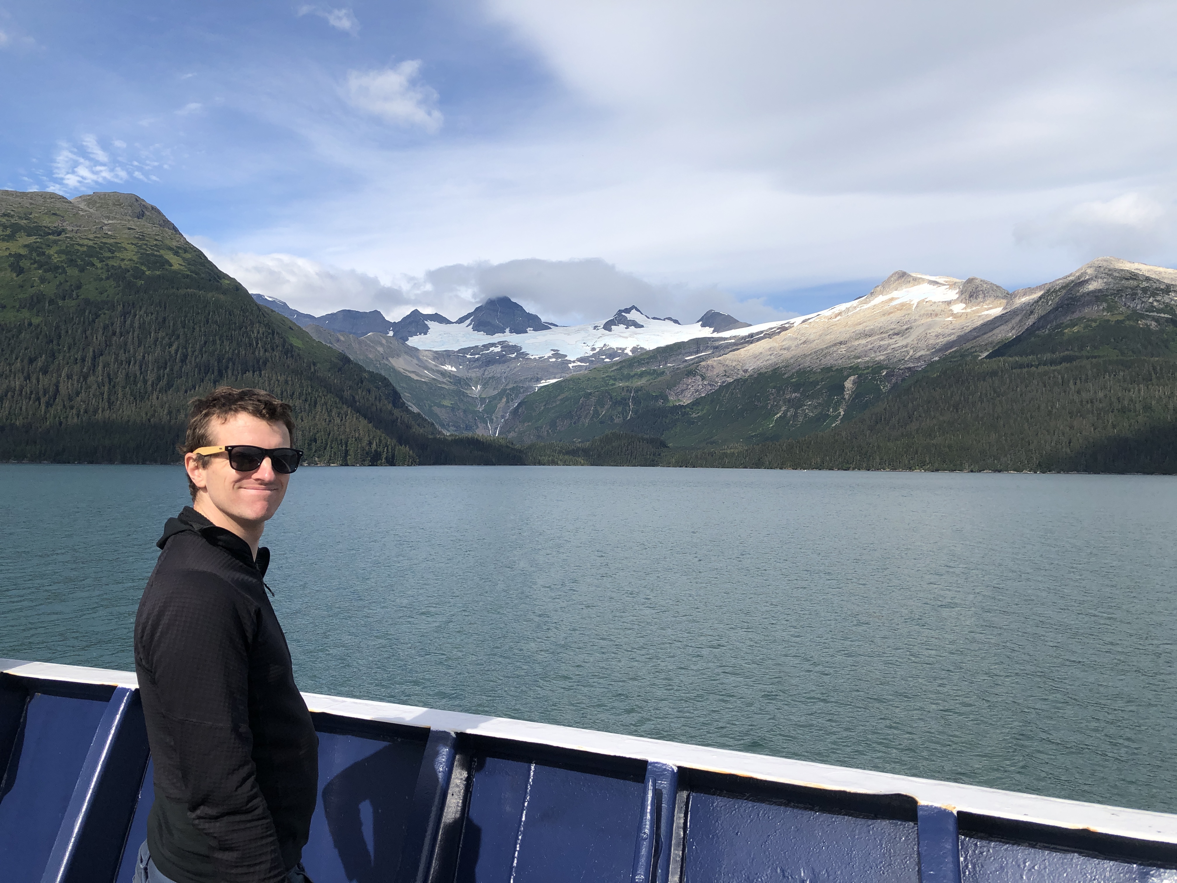 bryan looking happy on ferry from whittier to valdez with mountains and glaciers in the background of the prince william sound